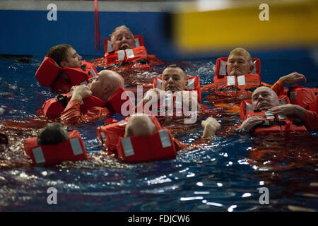 La gente di mare e i lavoratori offshore con giubbotti salvagente galleggiante in una piscina durante il mare la formazione di sopravvivenza. Foto Stock