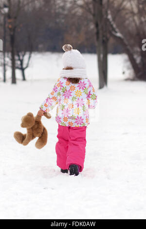 Vista posteriore della ragazza camminare con Teddy bear su una giornata invernale Foto Stock