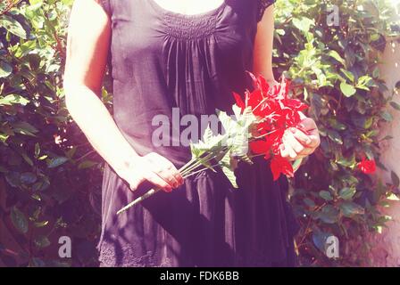 Donna che mantiene i fiori Foto Stock