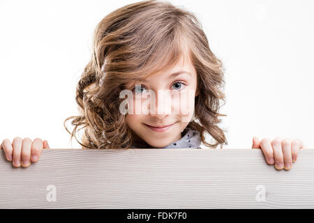 Bambina collocata dietro un pannello di legno a sorridere a voi Foto Stock