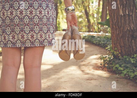 Vista posteriore di una donna holding paio di scarpe Foto Stock