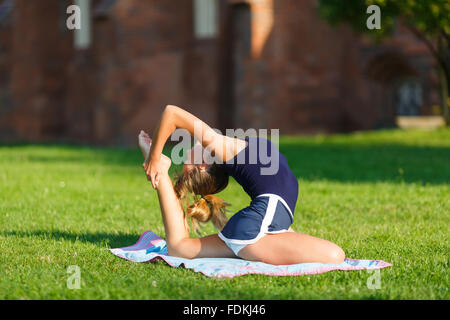 Ragazza giovane e carina facendo esercizi yoga outdoor Foto Stock