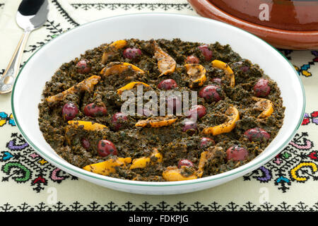 Piatto con spinaci marocchino, conserve di limoni e olive su sfondo bianco Foto Stock