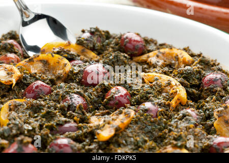 Piatto con spinaci marocchino, conserve di limoni e olive su sfondo bianco Foto Stock