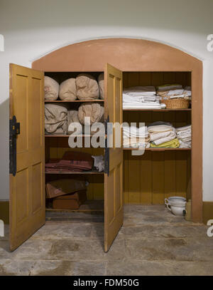 Credenza con coperte e lenzuola nel corridoio immobiliare nel seminterrato a Ickworth, Suffolk. Foto Stock