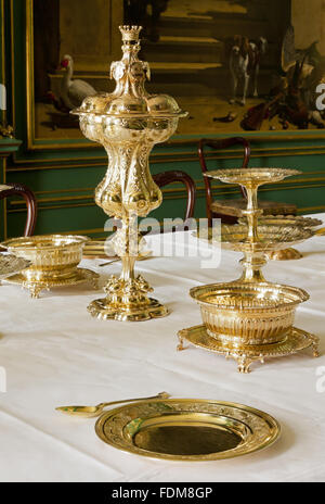 In argento dorato e oggetti in argento tra cui piatti da dessert e un dessert stand sul tavolo da pranzo nella sala Hondecoeter a Belton House, Lincolnshire. La grande coperta permanente cup è Vittoriana. Foto Stock