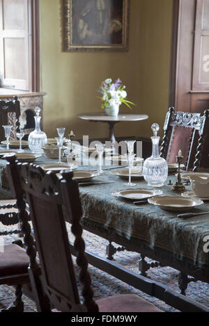 Tavolo fratino e rovere sedie da pranzo nel grande salone a Chastleton House, Oxfordshire. I vetri soffiati sul tavolo dispongono di aria e smalto bianco steli di torsione e la data a partire dalla prima metà del XVIII secolo. Foto Stock