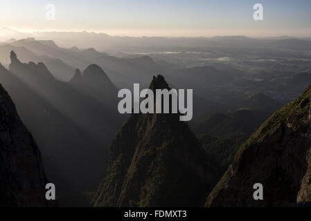 Raios de sol sobre montanhas no Parque Nacional da Serra dos Órgãos com Dedo de Deus à direita Foto Stock