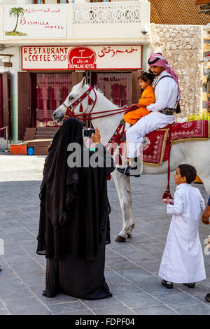 È montato un funzionario di polizia in posa per una foto con un bambino, il Souk Waqif, Doha, Qatar Foto Stock