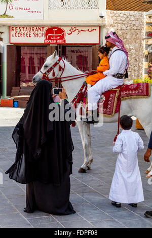 È montato un funzionario di polizia in posa per una foto con un bambino, il Souk Waqif, Doha, Qatar Foto Stock