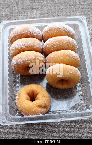 Le ciambelle ricoperte con glassa di zucchero in contenitore di plastica Foto Stock