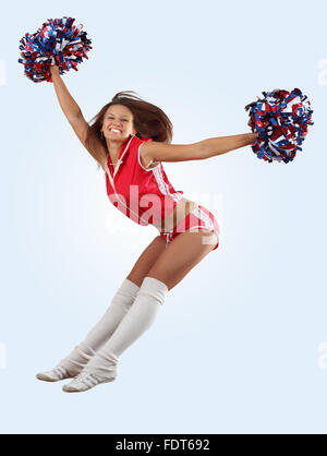 Uniformata cheerleader salta in aria in alto isolato su bianco. Foto Stock