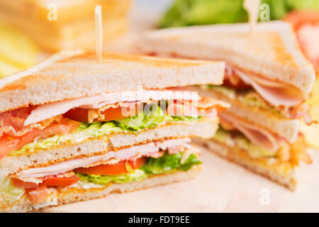 Un club sandwich su un tavolo rustico in condizioni di luce intensa. Foto Stock