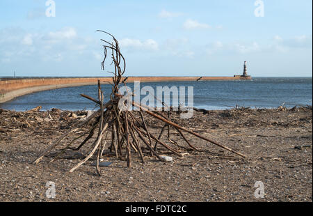 Un driftwood stack su Roker beach con il South Pier e il faro in background, Sunderland, North East England, Regno Unito Foto Stock