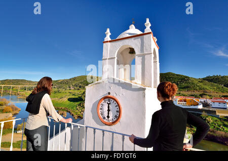 Portogallo Alentejo: due donne godendo di vista della torre medievale Torre de Relógio e fiume Guadiana in Mértola Foto Stock