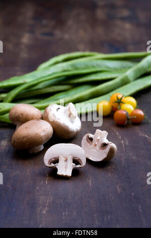 Funghi, pomodori e fagioli runner su una tavola di legno. Foto Stock