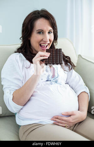 Donna incinta mangiare il cioccolato Foto Stock