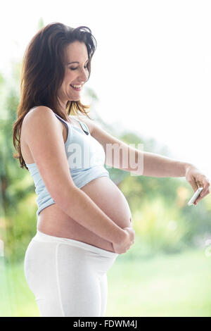 Donna incinta di scattare una foto del suo ventre Foto Stock