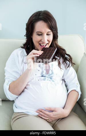 Donna incinta mangiare il cioccolato Foto Stock