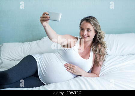 Donna incinta prendendo un selfie Foto Stock