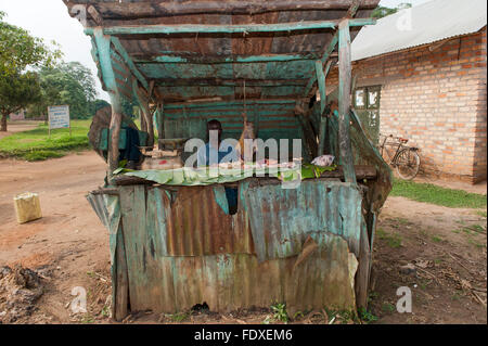 Macelleria ugandese nel suo negozio stradale costituito da fogli di stagno. Uganda. Foto Stock