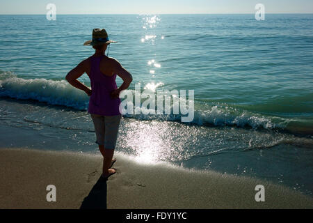 Una donna in spiaggia che guarda sull'oceano Foto Stock