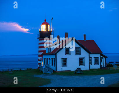 Lubec, Maine: West Quoddy Head Light in serata con la luce dal sorgere della luna scintillante tra le nuvole Foto Stock