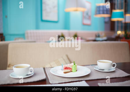 Due tazze di tè e una fetta di torta sul tavolo in cafe Foto Stock