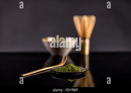 Polvere di tè verde nella piastra su sfondo nero Foto Stock