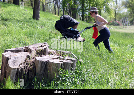 Berlino, Germania, donna spingendo il suo bambino in un passeggino in salita Foto Stock