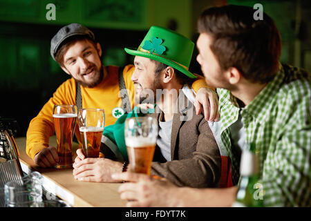 Un gruppo di giovani uomini in seduta pub e bere birra Foto Stock