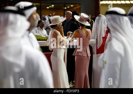 Dubai, Emirati arabi uniti, Uomini in costume tradizionale ed elegantemente vestito donna con cappello a gare Foto Stock
