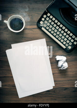 Una macchina da scrivere Vintage su una tavola di legno con il caffè e la carta. Vintage lo spazio in ufficio. carta bianca Foto Stock