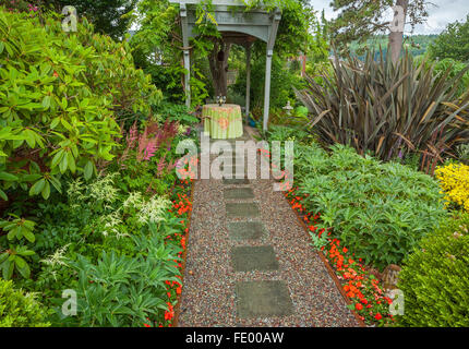 Vashon-Maury Island, WA: Giardino viale di impatiens conduce ad un piccolo e romantico tavolo sotto un pergolato di glicine. Foto Stock