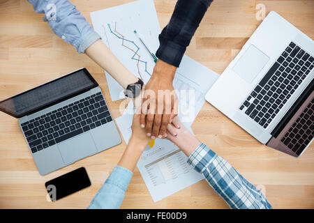 Gruppo multietnico di giovani che lavorano con i laptop e unire le mani insieme Foto Stock
