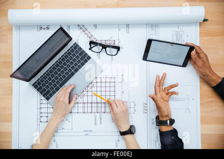 Vista dall'alto di un uomo e di una donna architetti disuccing blueprint e utilizzando laptop e tablet Foto Stock