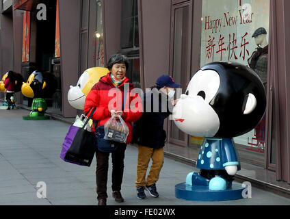 (160203) -- Shanghai, Febbraio 3, 2016 (Xinhua) -- i pedoni sono attratti da una statuetta di scimmia su Nanjing West Road a Shanghai in Cina orientale, Febbraio 3, 2016. Un totale di 100 incantevole figurine di scimmia sono stati collocati su Nanjing West Road, di una prospera commerciale street, a Shanghai, per creare un nuovo anno atmosfera. (Xinhua/Liu Ying) (lfj) Foto Stock