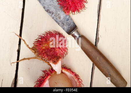 Tropicali freschi frutti di rambutan su tavola in legno rustico Foto Stock