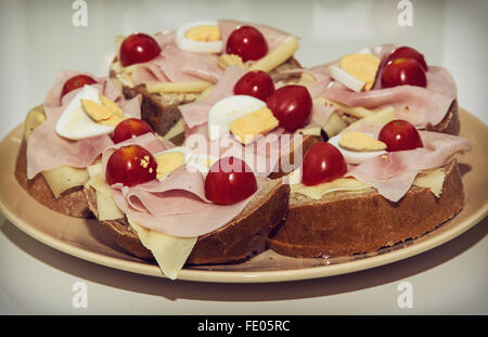 Panini saporiti con uova, formaggio, prosciutto e pomodori ciliegia sulla piastra. Tema alimentare. Foto Stock