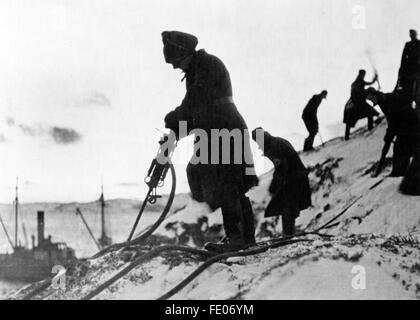 Il quadro della propaganda nazista mostra i lavori di costruzione dell'Organizzazione Todt sul fronte settentrionale. La foto è stata scattata nel gennaio 1944. Il testo della propaganda nazista sul retro della foto recita: "Aria compressa nell'estremo nord. I frontalieri dell'Organizzazione Todt preparano implosioni, mentre la costa inospitale dovrebbe essere resa ancora più difensiva." Fotoarchiv für Zeitgeschichtee - SENZA FILI - Foto Stock