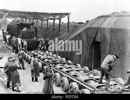 Unter dem Schutz deutscher Soldaten werden Geschütze für die Kanalbefestigungen an der Küste Frankreichs im Novembre 1942 transportiert, Aufnahmeort unbekannt. Unter der Kennung 'Organizzazione Todt' wurden Befestigungs-, Verteidigungseinrichtungen und Bunker mit Abschussbasis entlang der Atlantikküste zur Abwehr gegen die Alliierten erbaut. Die nationalsozialistische Propaganda schreibt am 02.11.1942 auf der Rückseite des Bildes: "zwei Dutzend Räder tragen den Koloss. Ein schweres Geschütz für die Kanalbefestigungen wurde bis un seinen Standort auf einem Spezialwagen herangebracht. Diese auf zw Foto Stock