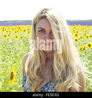 Donna in piedi nel campo di girasoli Foto Stock