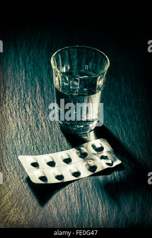 Un bicchiere di acqua e un blister con compresse Foto Stock