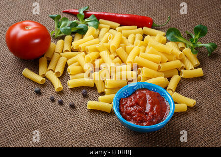Rigatoni pasta grezza sullo sfondo di iuta Foto Stock