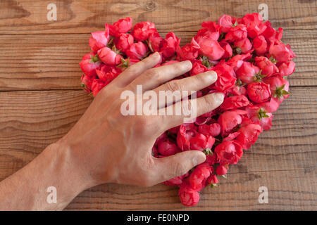 Cuore di rose rosse in background in legno, ricoperto da un lato di rappresentare sentimenti personali Foto Stock