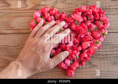 Cuore di rose rosse in background in legno, ricoperto da un lato di rappresentare sentimenti personali Foto Stock