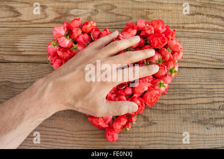 Cuore di rose rosse in background in legno, ricoperto da un lato di rappresentare sentimenti personali Foto Stock