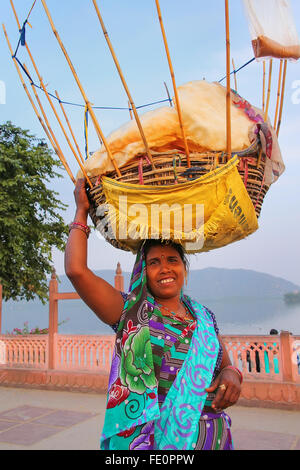 Donna indiana con cestello sul suo capo vendono spuntini da uomo Sagar lago a Jaipur, Rajasthan, India. Foto Stock