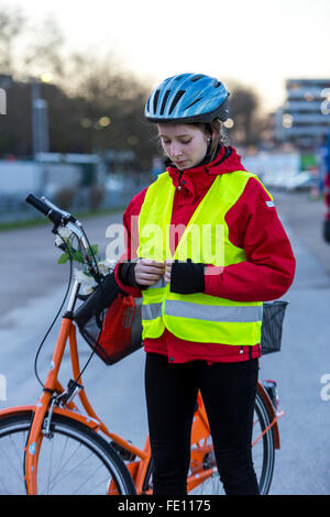 Ciclista messo su abbigliamento di sicurezza, bike casco e gilet riflettente per bici sicurezza, una buona visibilità di notte nel traffico Foto Stock