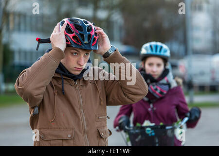 Ciclista messo su abbigliamento di sicurezza, bike casco e gilet riflettente per bici sicurezza, una buona visibilità di notte nel traffico Foto Stock